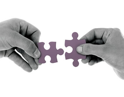 Two hands joining two puzzle pieces, small.